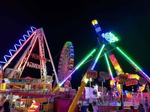 Atracciones de feria con luces de neón en movimiento durante la noche