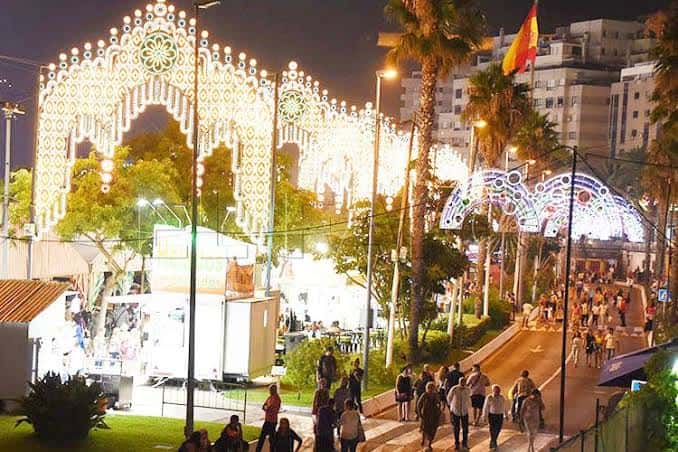 Entrada principal del recinto ferial con arcos decorativos iluminados y banderas