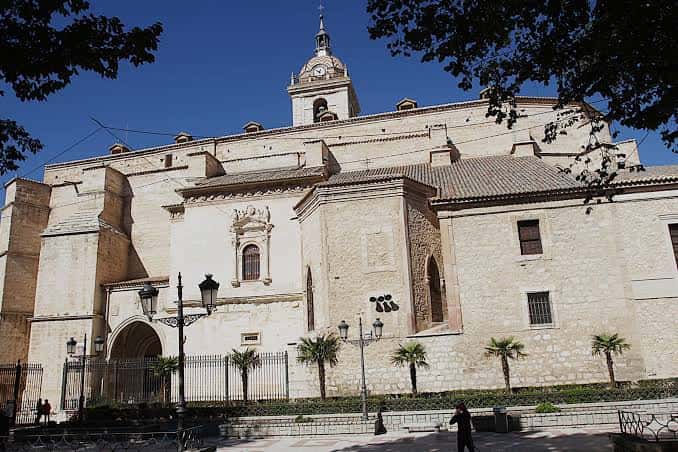 Exterior de la catedral con detalles arquitectónicos, farolas y palmeras en primer plano bajo luz diurna