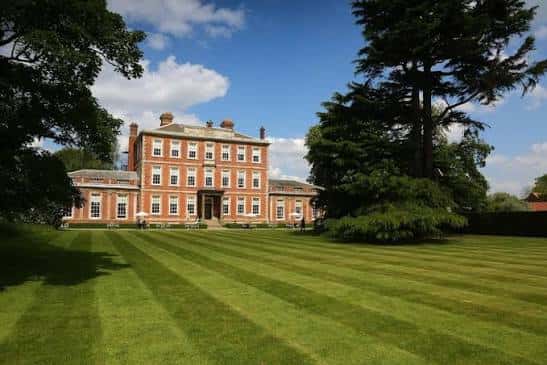 Vista frontal de Middlethorpe Hall con jardines bien cuidados y cielo azul