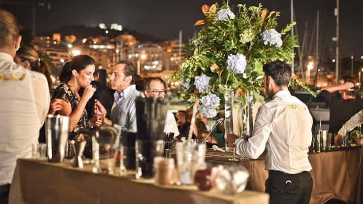 Evento social nocturno en el Club de Mar con barra y decoración floral