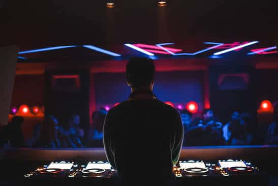 Vista desde atrás del DJ en el escenario con luces de fondo
