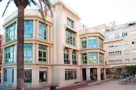 Vista exterior del Centre Cívic Casa Orlandai con fachada neoclásica y palmera