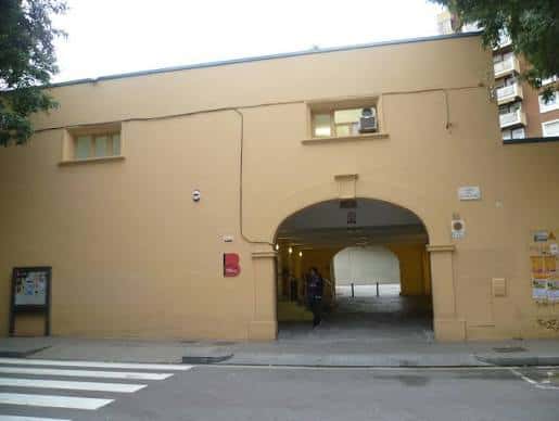Vista exterior del edificio con fachada amarilla y arco de entrada