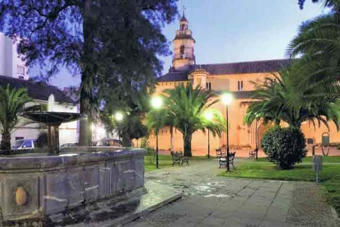 Vista nocturna de la Plaza de la Magdalena con la fuente iluminada y la iglesia de fondo