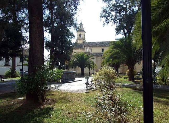 Vista de la Plaza de la Magdalena desde un sendero con árboles y la iglesia al fondo