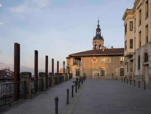 Plaza de la Cuesta de San Vicente al atardecer con la torre de la iglesia iluminada