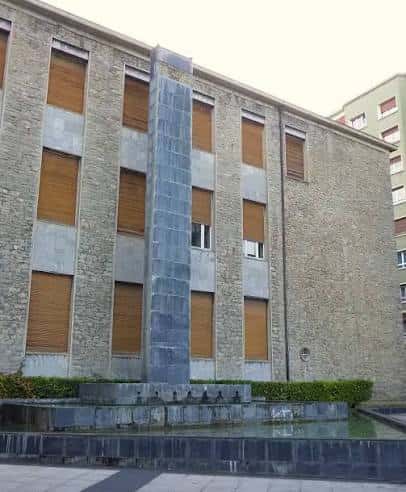 Detalle del obelisco y fuente en la plaza con fachada de piedra al fondo