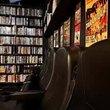 Sala de cine privada con butacas y pared de videos