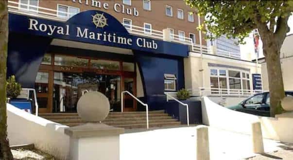 Entrada principal del Royal Maritime Club con letrero azul y detalles arquitectónicos marítimos