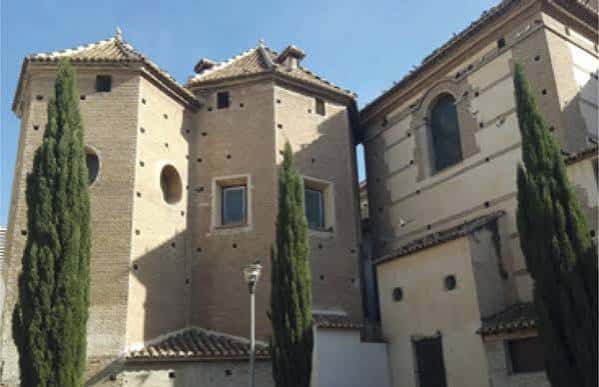 Vista exterior de la fachada histórica de la Parroquia San Juan de la Cruz con torres y cipreses