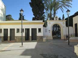Entrada principal de la parroquia con arco decorativo y palmeras bajo cielo despejado