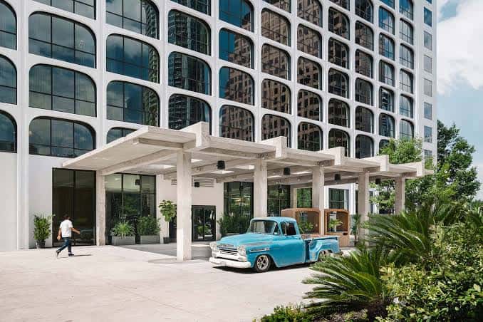 Entrada principal del hotel The LINE Austin con marquesina de hormigón y camión vintage azul