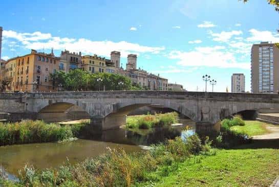 Vista amplia del puente de piedra sobre el río Onyar con edificios históricos al fondo