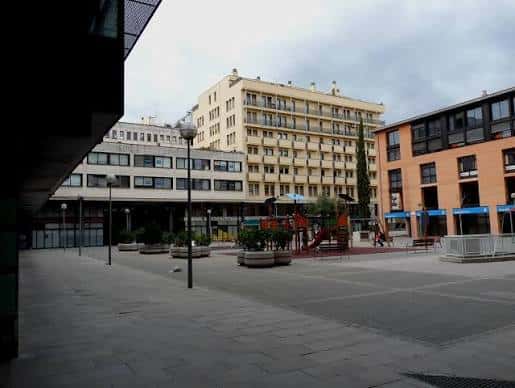 Vista general de la plaza Josep Pla con edificios modernos y zona de juegos infantiles
