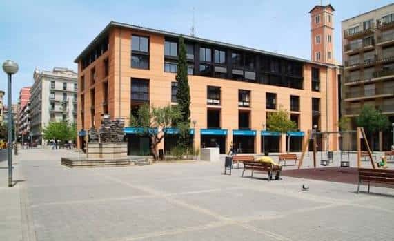 Fachada del edificio de la plaza Josep Pla con zona de juegos al fondo