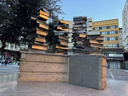 Escultura de libros apilados en la plaza Josep Pla al atardecer