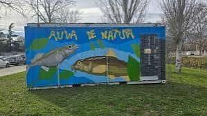 Vista exterior del contenedor pintado con el nombre Aula de Natura y dibujos de peces