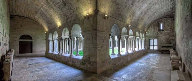 Claustro interior con arcos de medio punto y columnas sobre patio ajardinado