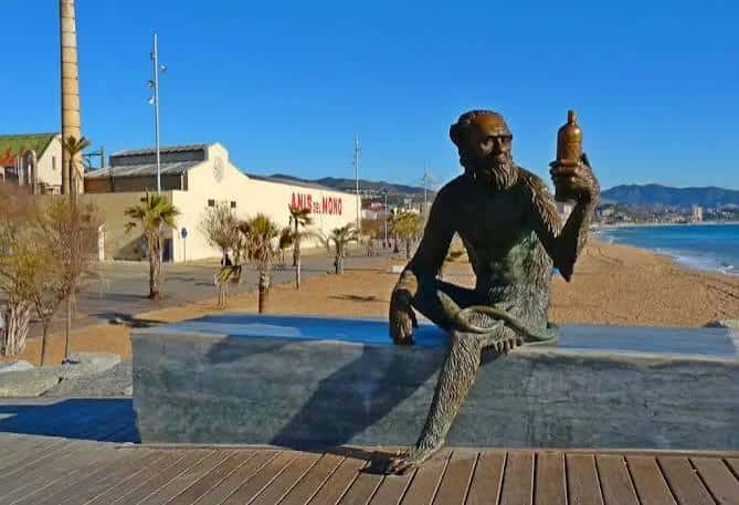 Estatua del mono con botella de Anís del Mono frente a la playa