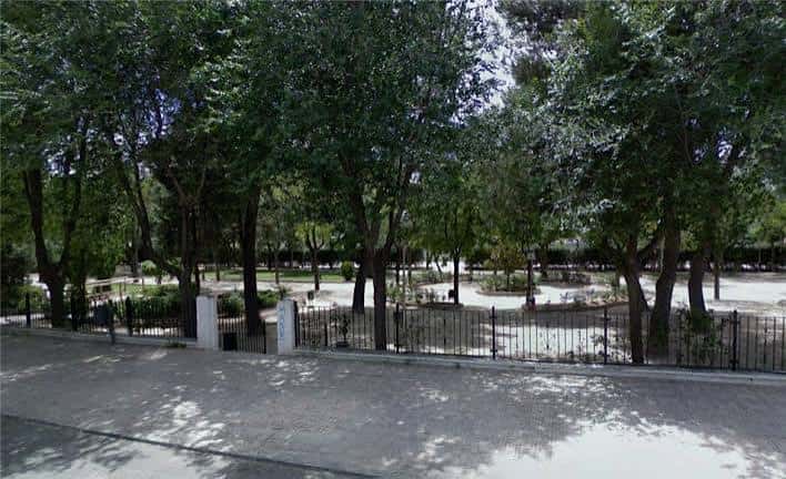 Vista del Parque San Isidro con árboles frondosos y zona de juegos al fondo