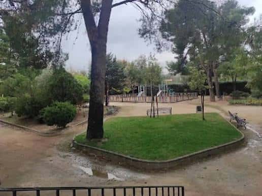Área de juegos infantiles en el Parque San Isidro con césped y árboles