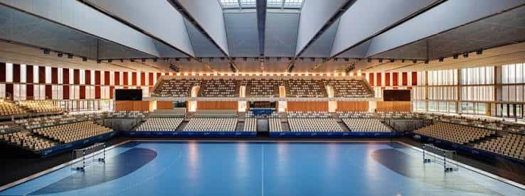 Interior del pabellón deportivo con pista de baloncesto y gradas vacías