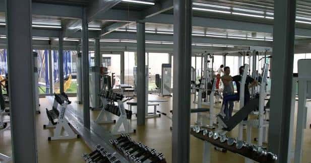Gimnasio del polideportivo con equipamiento deportivo y grandes ventanales