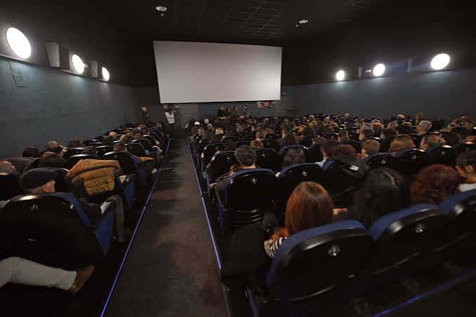 Interior de la sala de cine con butacas azules y pantalla grande durante una proyección