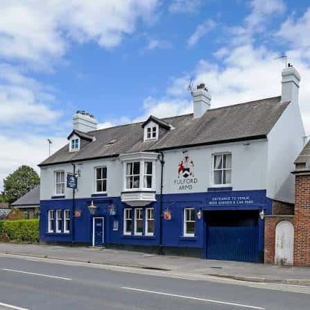 Fachada exterior del Fulford Arms en York, pub tradicional con paredes blancas y azules bajo cielo despejado
