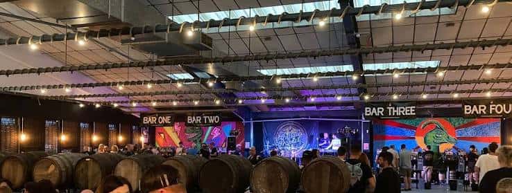 Interior del taproom con barriles de cerveza, barra y escenario para eventos en vivo