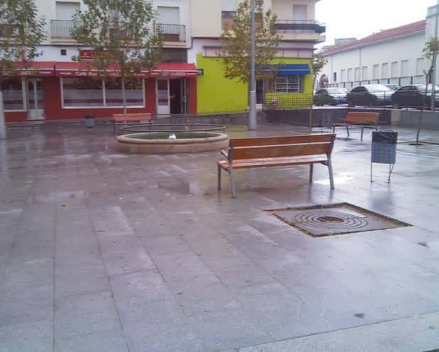 Plaza de Pizarro en Mérida con fuente y bancos bajo la lluvia