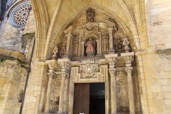 Vista detallada de la portada principal de la Iglesia de San Vicente con su escultura central y decoración gótica