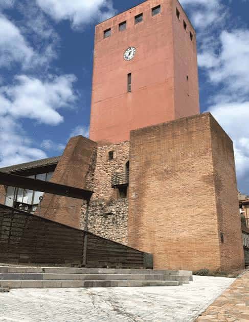 Vista frontal de la Torre del Reloj en Gijón con cielo azul y nubes
