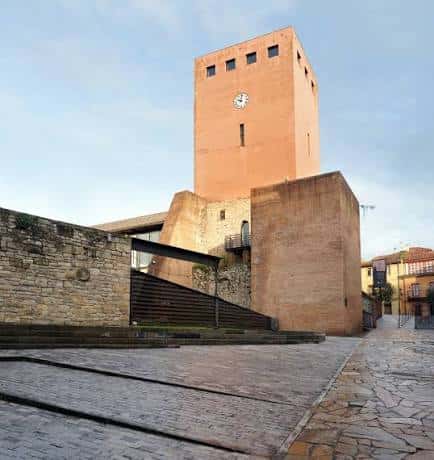 Plaza empedrada frente a la Torre del Reloj con arquitectura de ladrillo y piedra