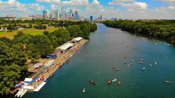 Vista aérea del Texas Rowing Center con el skyline de Austin al fondo y múltiples embarcaciones en el agua