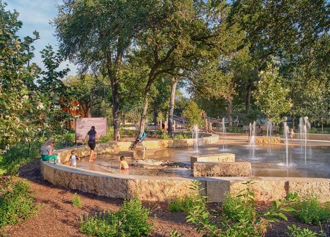 Área de juegos con fuentes y niños jugando en Pease Park
