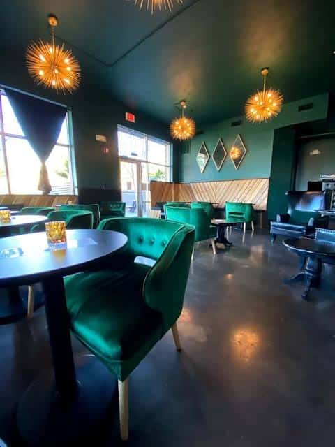 Interior elegante del lounge con sillas de terciopelo verde y lámparas de sol doradas