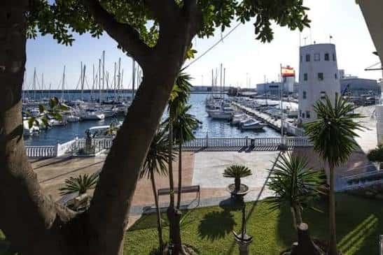 Vista panorámica del puerto deportivo con embarcaciones amarradas y el edificio blanco del club náutico al fondo