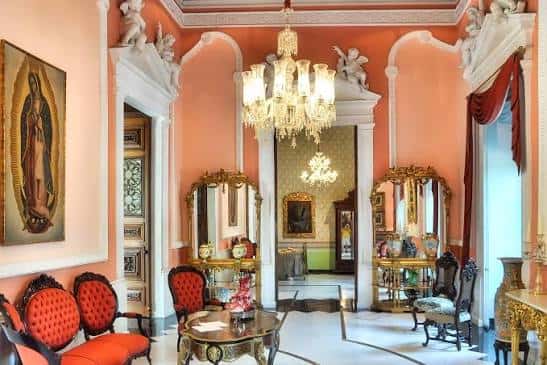Salón interior decorado con estilo barroco, muebles rojos, espejos dorados y candelabros colgantes