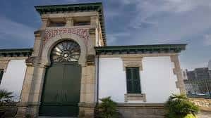 Fachada frontal del antiguo matadero municipal con arco decorativo y puerta verde