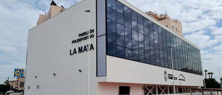 Vista exterior del Pabellón Polideportivo La Mata con fachada blanca y cristalera