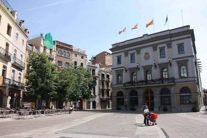 Fachada del Ayuntamiento de Igualada con banderas ondeando en un día soleado