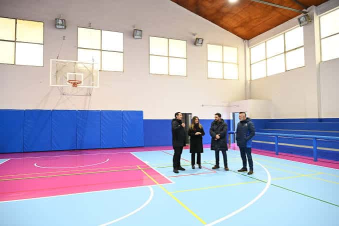 Interior del polideportivo con pista de baloncesto y gradas azules