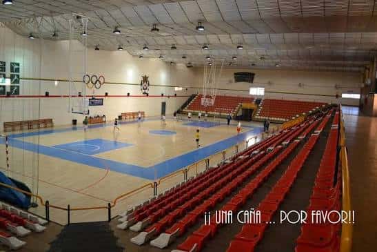 Vista general del pabellón deportivo con canchas y asientos rojos
