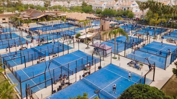 Pistas de pádel en uso durante el día con jugadores activos y entorno tropical