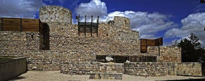 Vista panorámica de las murallas y torres del Castillo de Burgos bajo un cielo azul con nubes