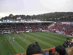 Interior del estadio durante un partido con espectadores y césped verde