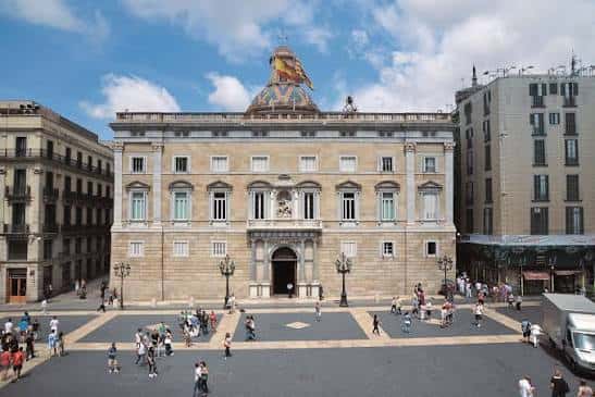 Plaza de Sant Jaume con el Palau de la Generalitat al fondo y personas caminando