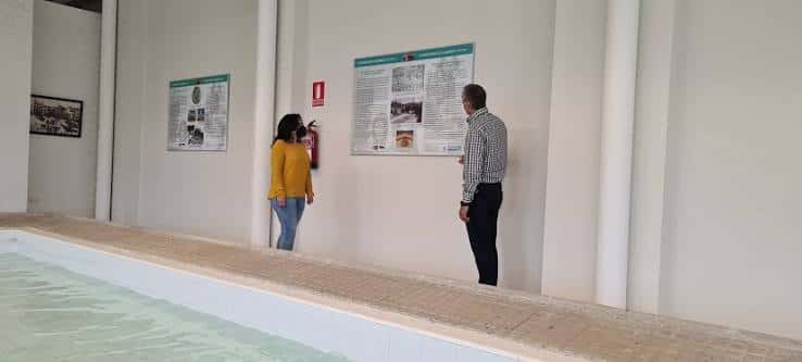 Interior del antiguo lavadero mostrando la piscina de agua y paneles informativos
